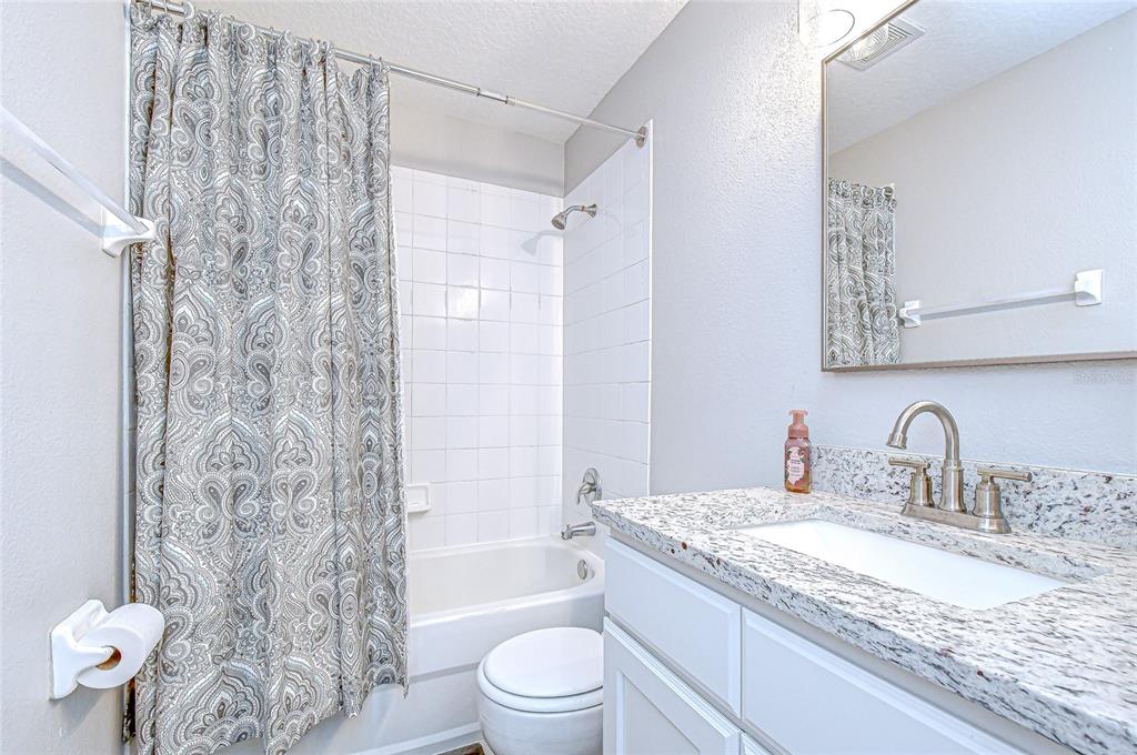 228 Hardcastle Place Valrico, FL 33594 - Photo 15 of 22 a bathroom with a granite countertop sink a toilet and shower curtain