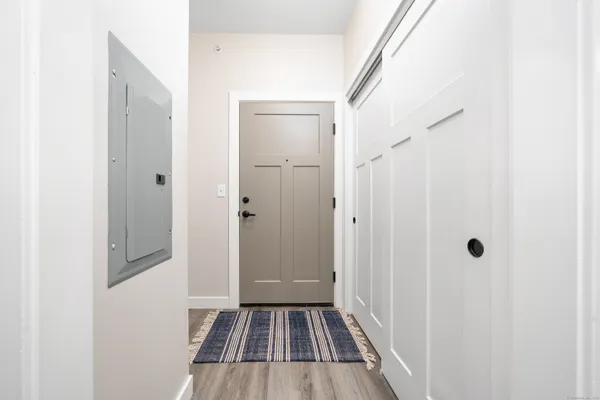 a view of a hallway with wooden floor and a bathroom