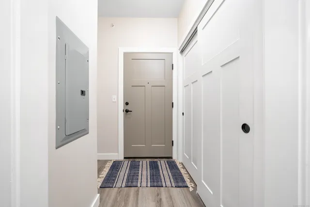 a view of a hallway with wooden floor and a bathroom