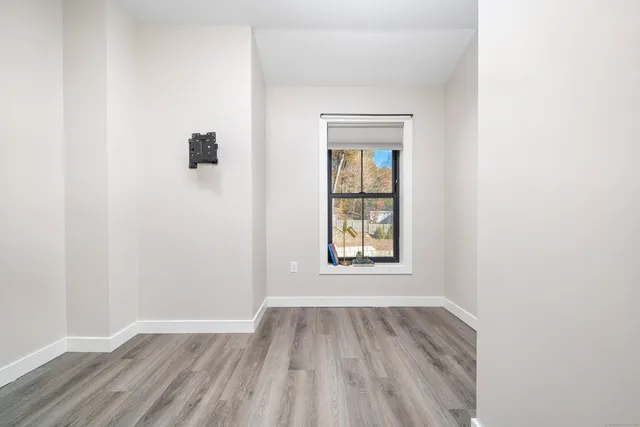 an empty room with wooden floor and windows