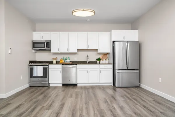 a kitchen with a refrigerator and white cabinets