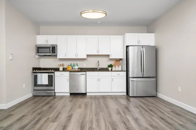 a kitchen with a refrigerator and white cabinets