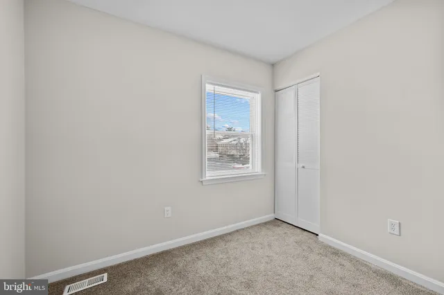 a view of an empty room with window and closet area