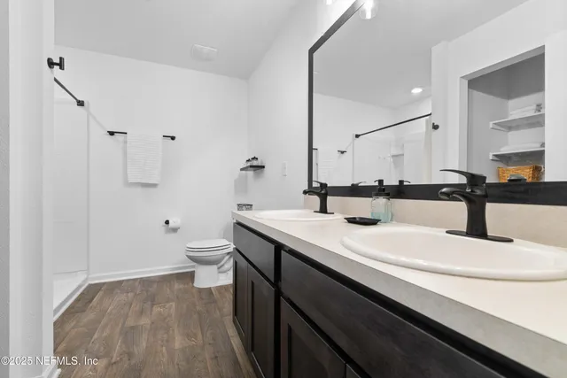 a bathroom with a double vanity sink toilet and a mirror