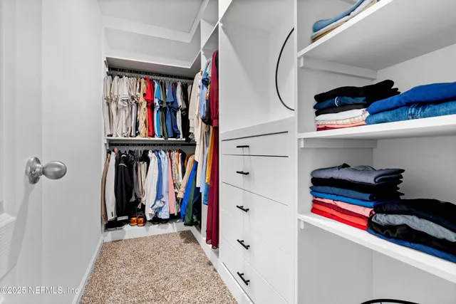 a view of walk in closet with clothes and shoes