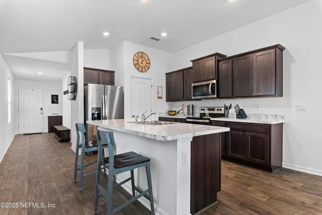 a kitchen with stainless steel appliances granite countertop a stove top oven a sink and a refrigerator