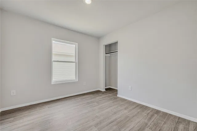 an empty room with wooden floor and window
