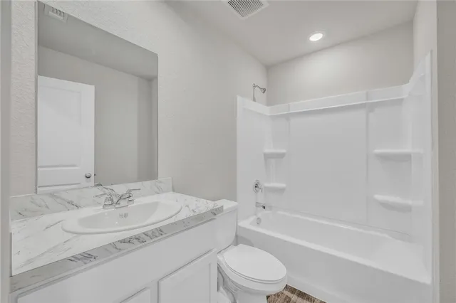 a bathroom with a granite countertop sink a toilet and a bathtub