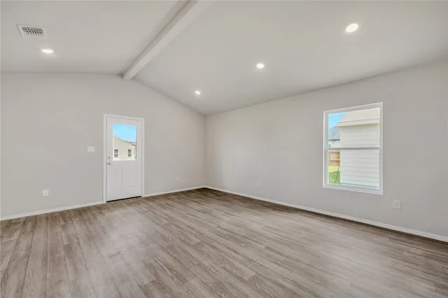 an empty room with wooden floor and window