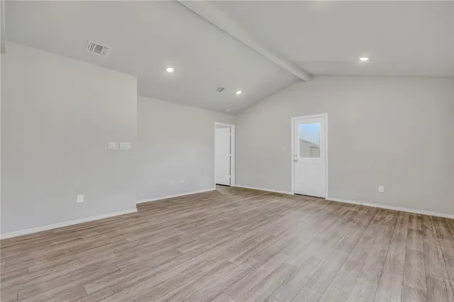 a view of an empty room with wooden floor and closet