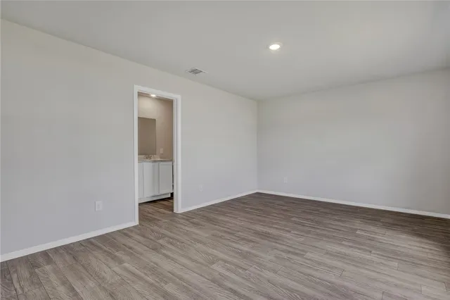 a view of an empty room with wooden floor and closet