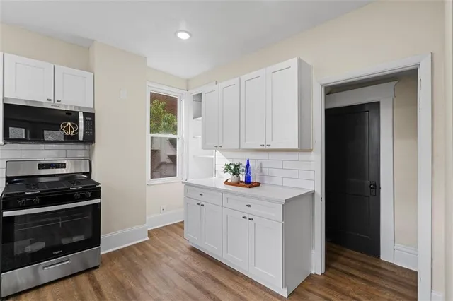 a kitchen with granite countertop white cabinets and stainless steel appliances