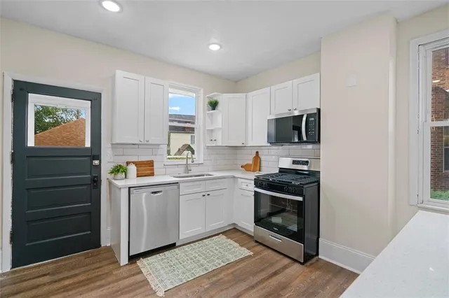 a kitchen with a sink cabinets stainless steel appliances and wooden floor