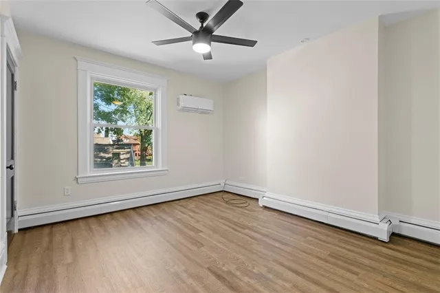 an empty room with wooden floor chandelier fan and windows