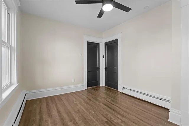 an empty room with wooden floor fan and windows