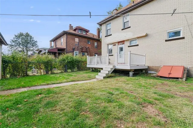 a view of a house with a big yard potted plants and large tree