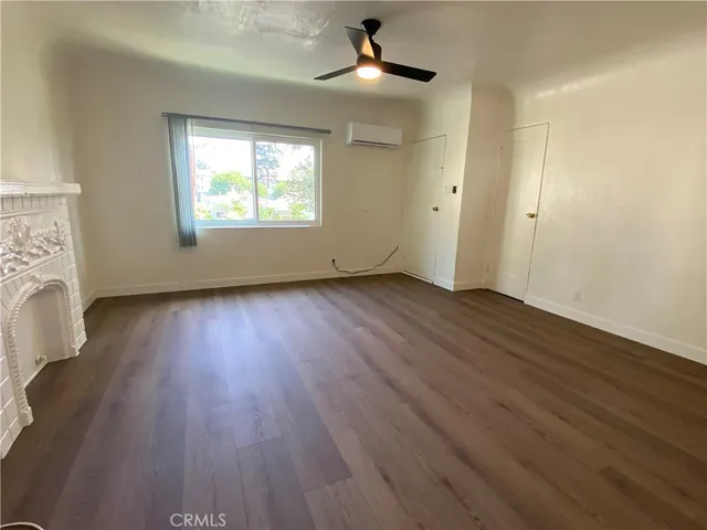an empty room with wooden floor chandelier fan and windows