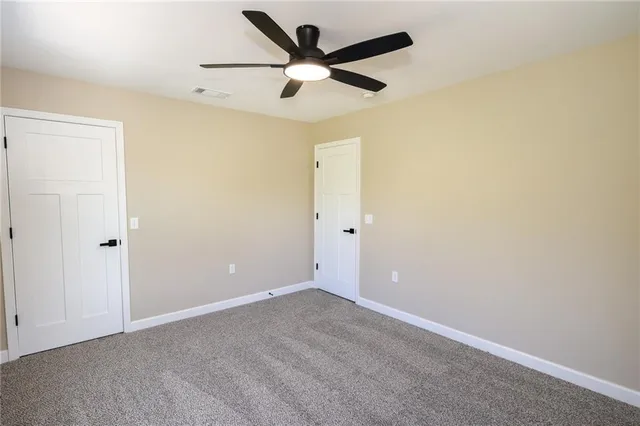 an empty room with ceiling fan and window