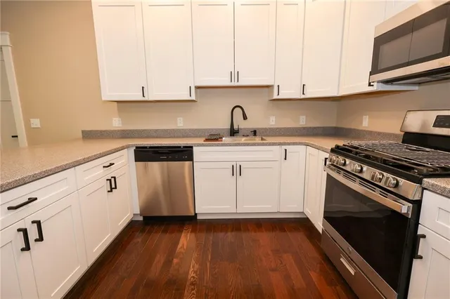 a kitchen with stainless steel appliances granite countertop a stove a sink and white cabinets
