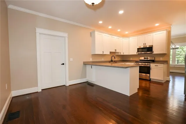 a kitchen with stainless steel appliances granite countertop a stove top oven a sink and a microwave