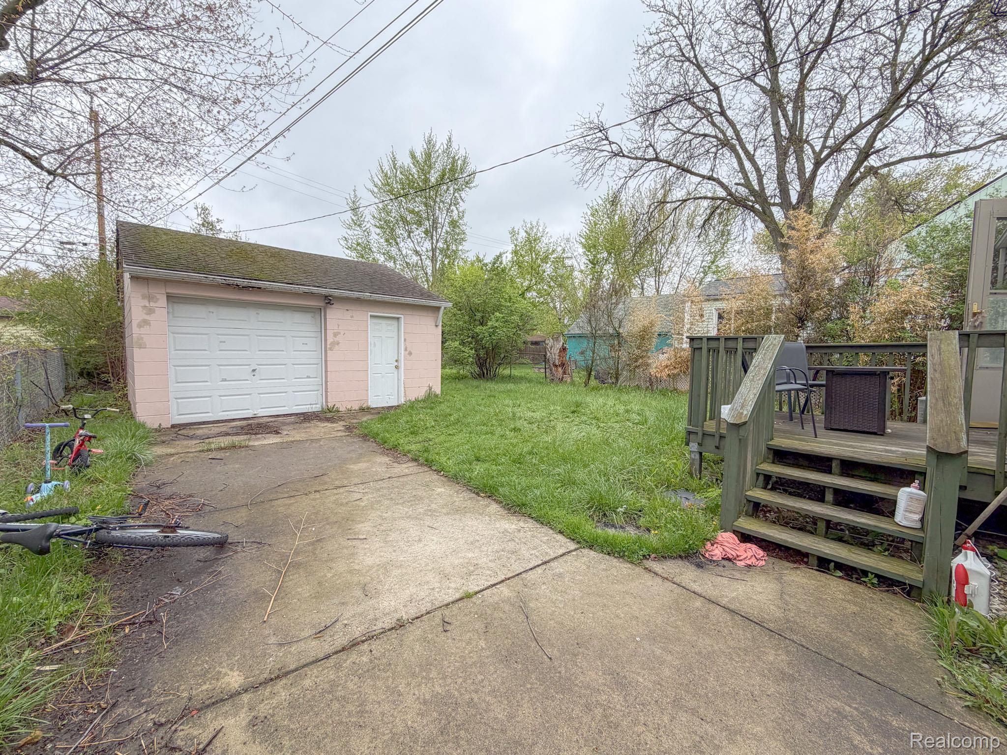 24811 Valley Avenue Eastpointe, MI 48021 - Photo 20 of 22 View of yard with a deck, concrete driveway, an outdoor structure, and a garage