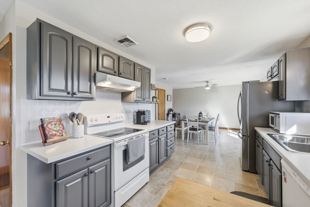 20 Connolly Street Springfield, MA 01151 - Photo 15 of 41 a kitchen with stainless steel appliances granite countertop a stove top oven a sink a dining table and chairs with wooden floor