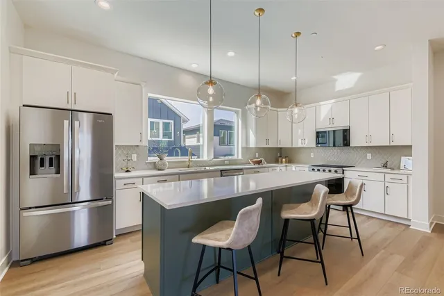 a kitchen with stainless steel appliances granite countertop a island a stove a refrigerator a white cabinets and wooden floor