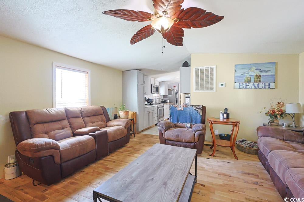 1911 Abba Court Conway, SC 29526 - Photo 4 of 25 Living room featuring wood finished floors, a glass covered fireplace, an AC wall unit, a textured ceiling, and a ceiling fan