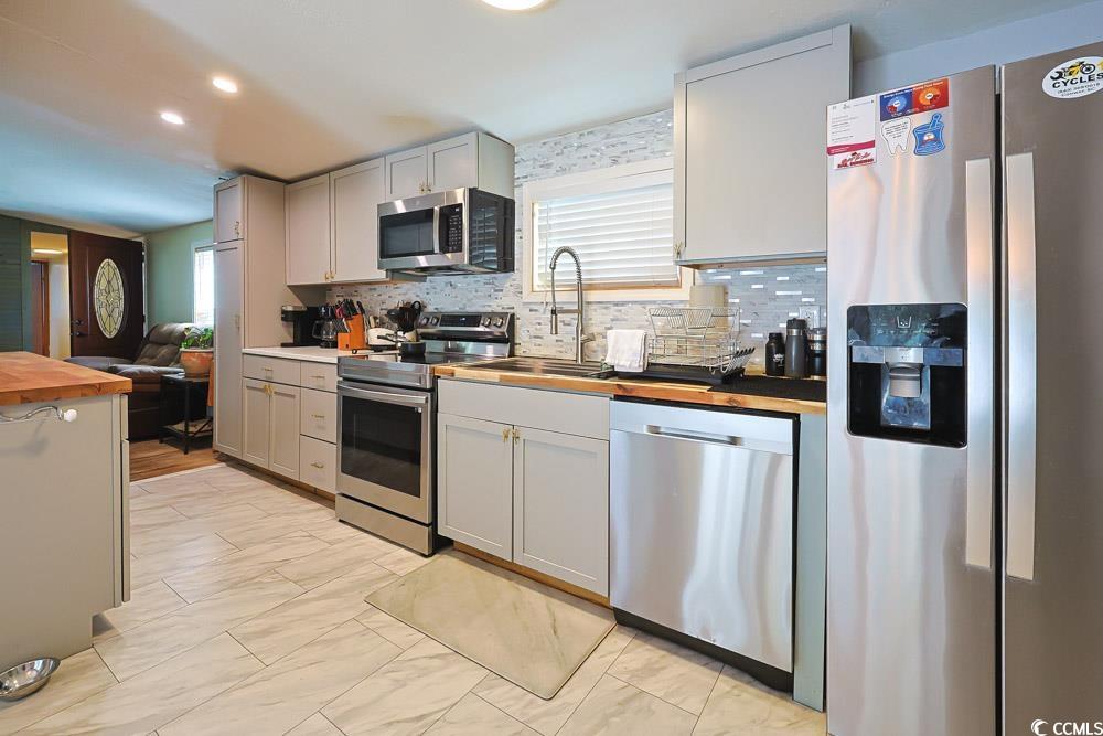 1911 Abba Court Conway, SC 29526 - Photo 6 of 25 Kitchen with butcher block counters, stainless steel appliances, tasteful backsplash, light marble finish flooring, and white cabinets
