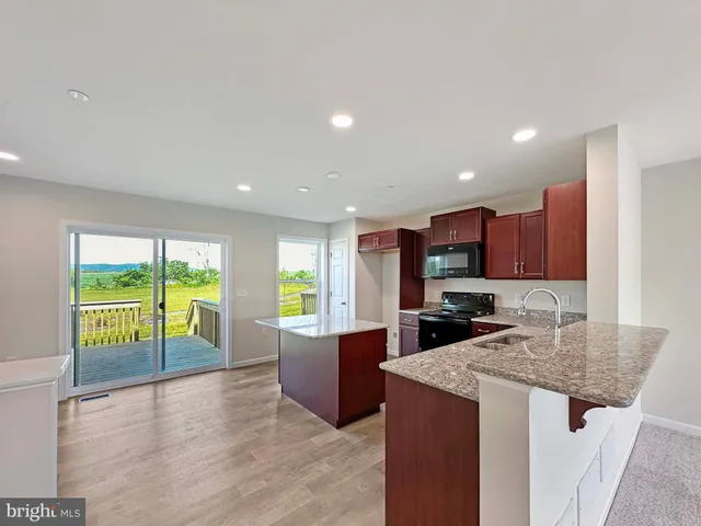 a kitchen with kitchen island granite countertop a stove a sink a refrigerator and a dining table with wooden floor
