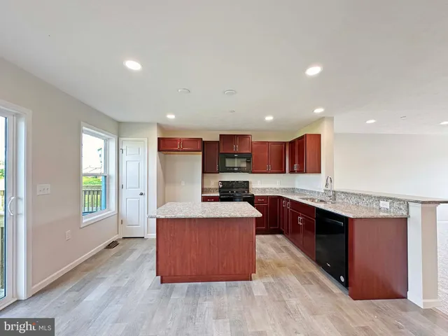 a kitchen with stainless steel appliances granite countertop a stove a sink dishwasher and a refrigerator with wooden floor