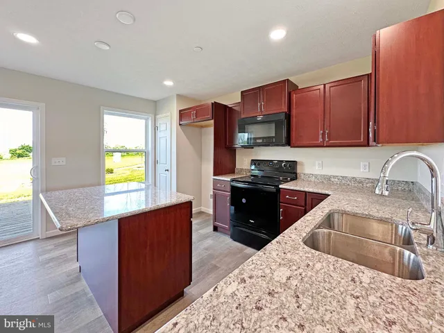 a kitchen with granite countertop a refrigerator and a sink