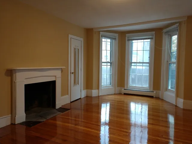 a view of an empty room with glass door and wooden floor