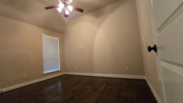 an empty room with wooden floor fan and window