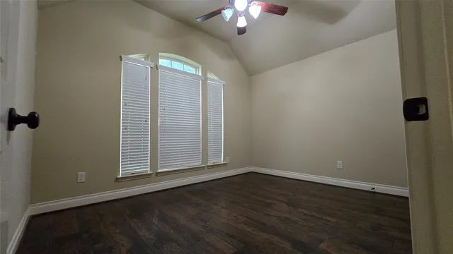an empty room with wooden floor fan and window