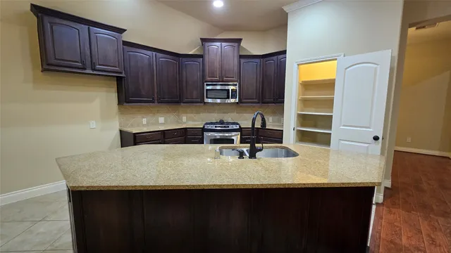 a kitchen with stainless steel appliances granite countertop a stove kitchen island a sink and a refrigerator