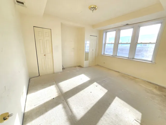 a view of a bedroom with wooden floor and windows