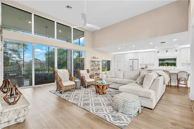 a living room with furniture large windows and wooden floor