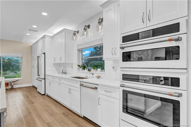 a kitchen with stainless steel appliances kitchen island granite countertop a stove and white cabinets