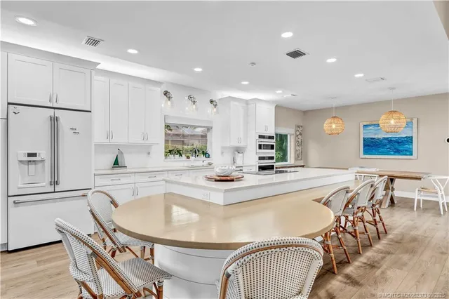 a kitchen with stainless steel appliances granite countertop a dining table chairs and granite counter tops