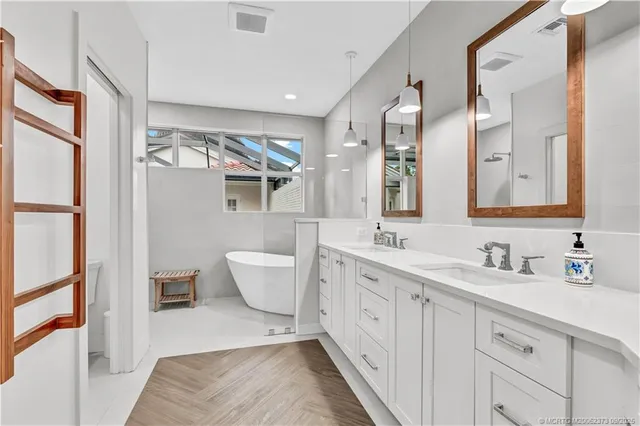 a spacious bathroom with a double vanity sink a mirror and a bathtub