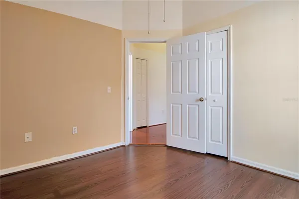 a view of an empty room with wooden floor and closet