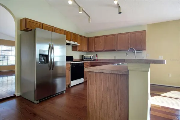 a kitchen with stainless steel appliances granite countertop a refrigerator a sink a stove and a wooden floors