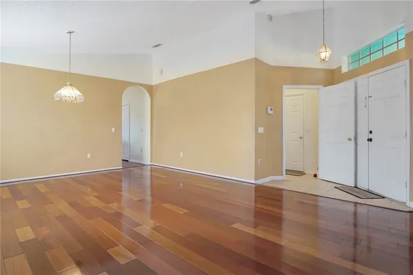 a view of an empty room with window and chandelier fan