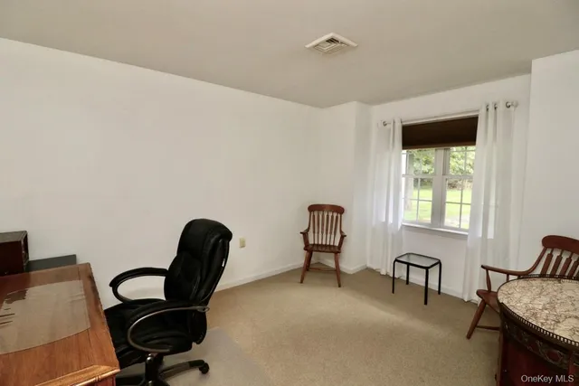 a view of a workspace with furniture and a window