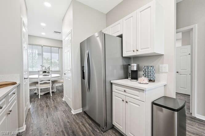7935 Mahogany Run Lane, Unit 725 Naples, FL 34113 - Photo 24 of 27 a kitchen with a refrigerator a sink dishwasher and a stove with wooden floor