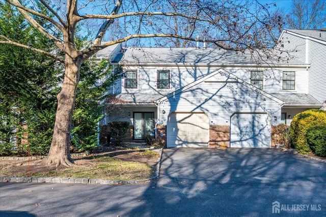 a view of a house with large tree and wooden fence