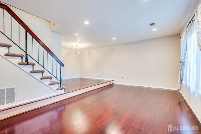 a view of an empty room with wooden floor and stairs