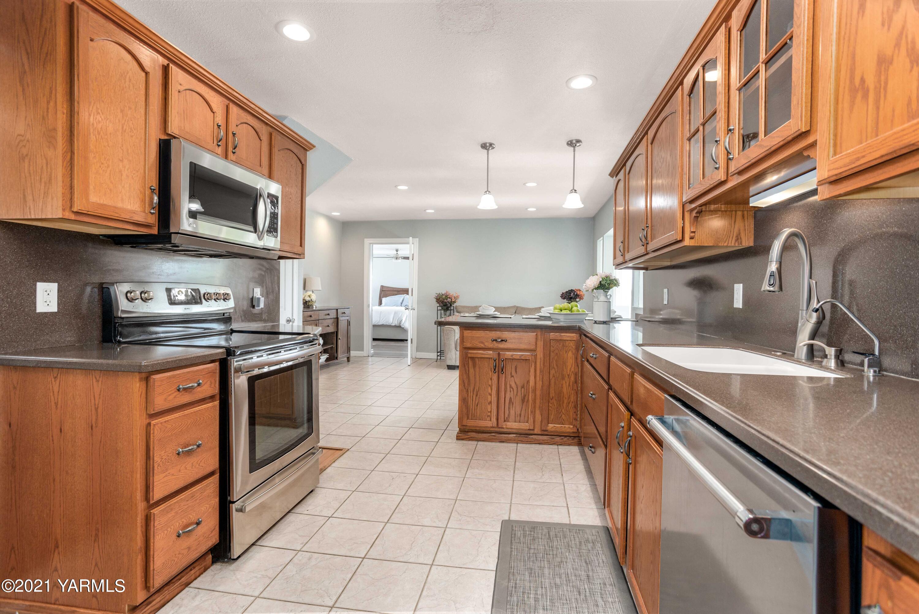 570 Chase Road Grandview, WA 98930 - Photo 11 of 42 a kitchen with stainless steel appliances granite countertop a stove a sink and a microwave