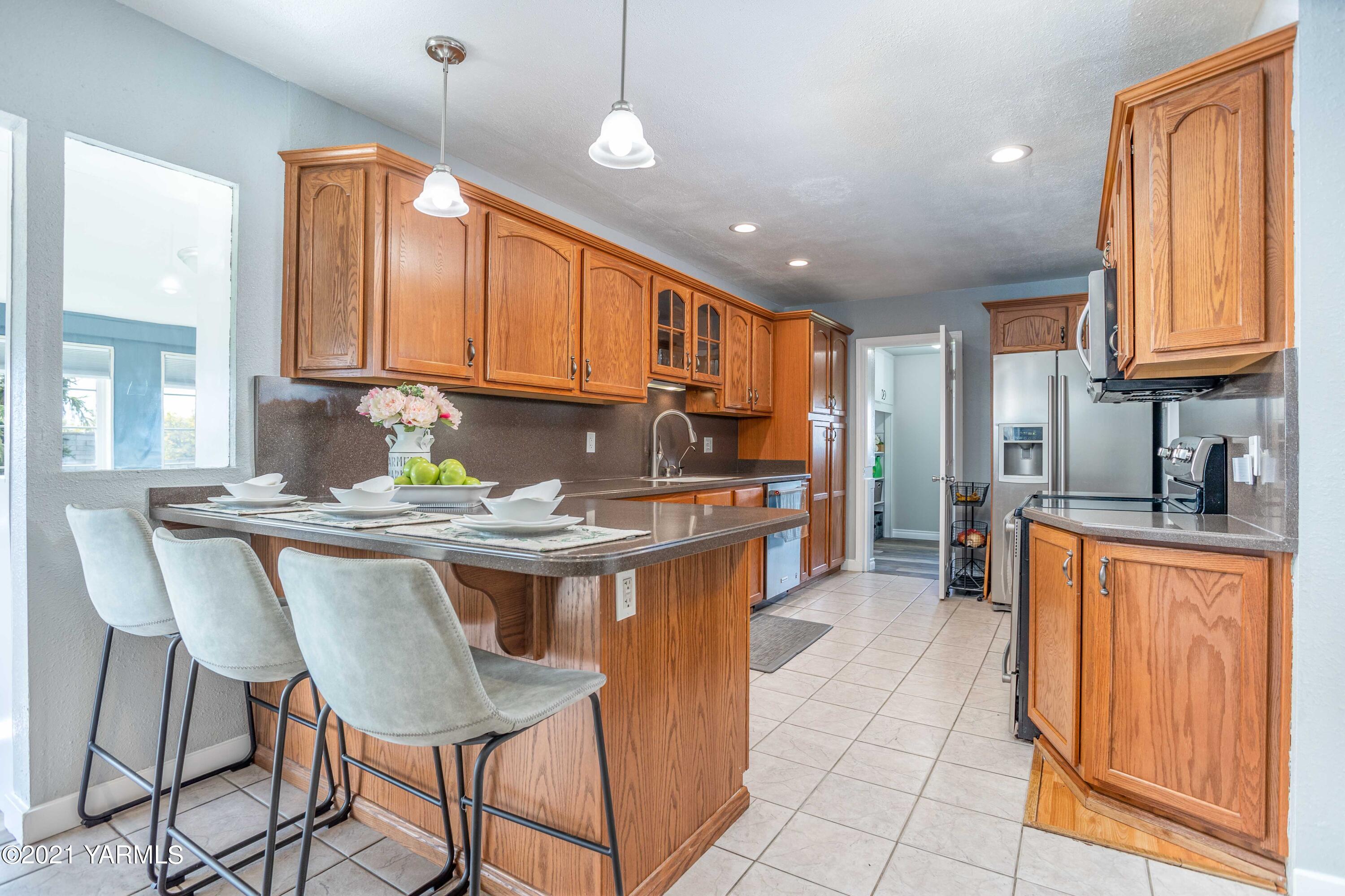570 Chase Road Grandview, WA 98930 - Photo 9 of 42 a kitchen with kitchen island granite countertop wooden cabinets a counter top space and stainless steel appliances